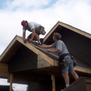 Photo of workers nailing tarpaper on new roof.